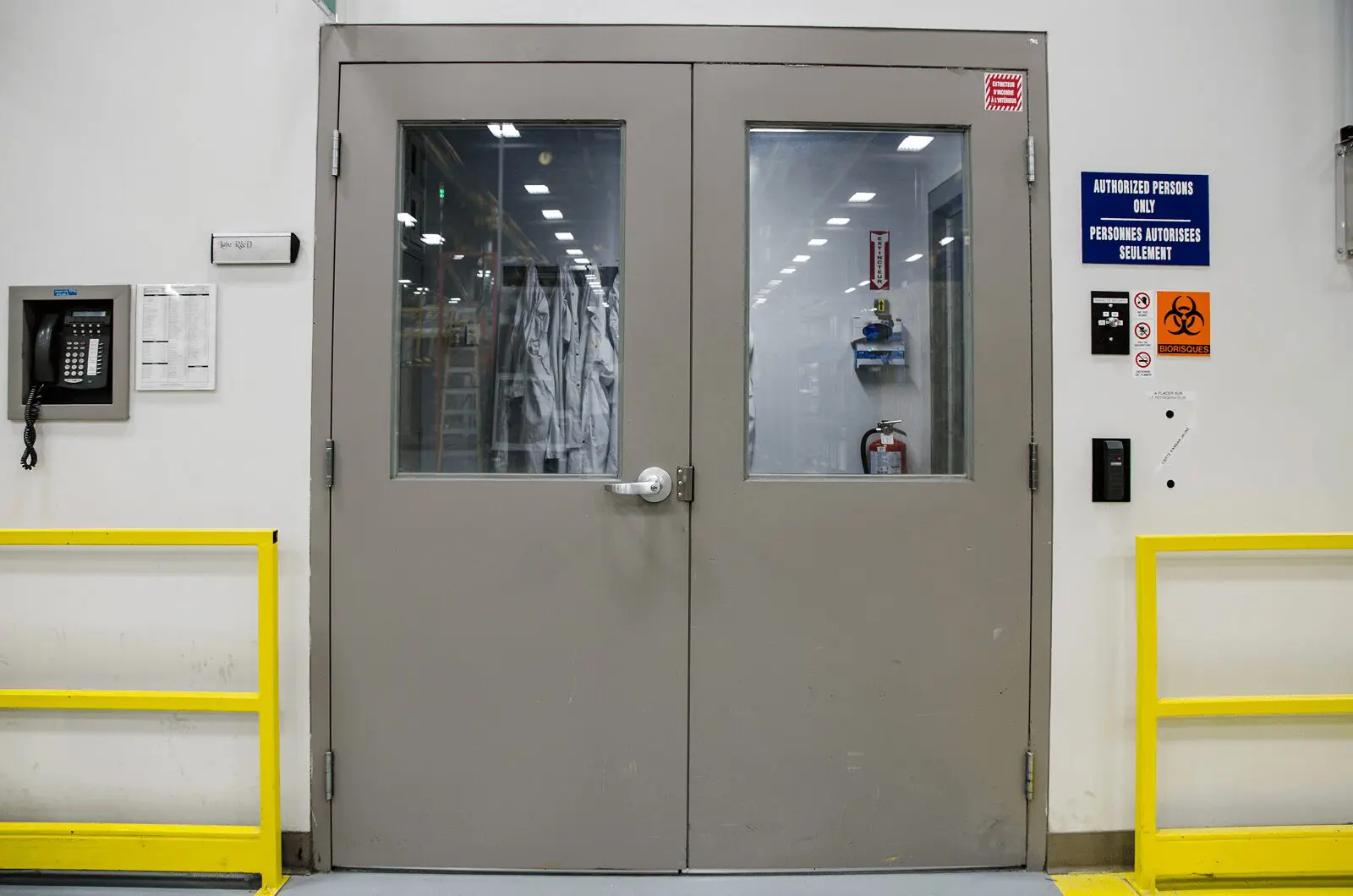 Gray lab door with warning signs posted.