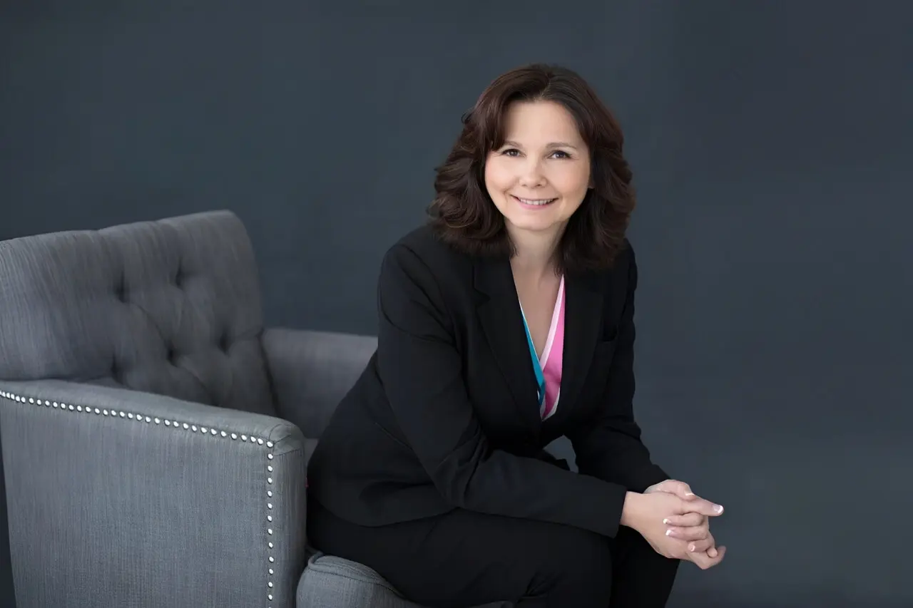 Smiling woman seated on a gray chair.